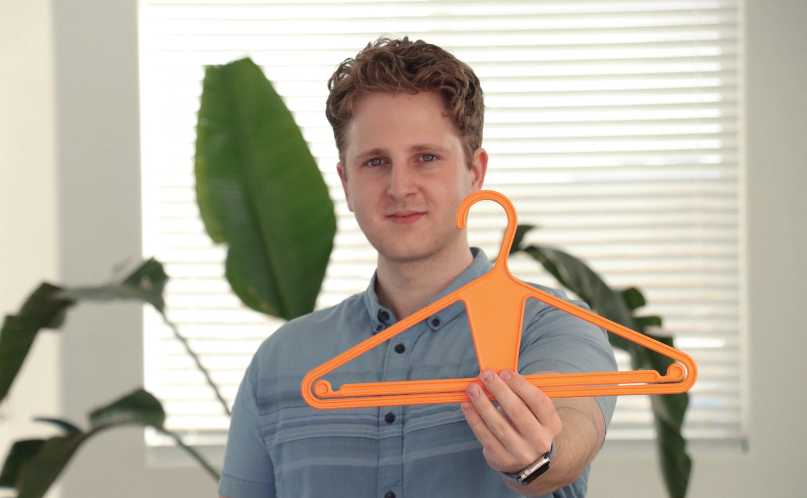 Kangaroo Founder Angus Willows holding a Kangaroo Hanger in the color Tangerine Orange